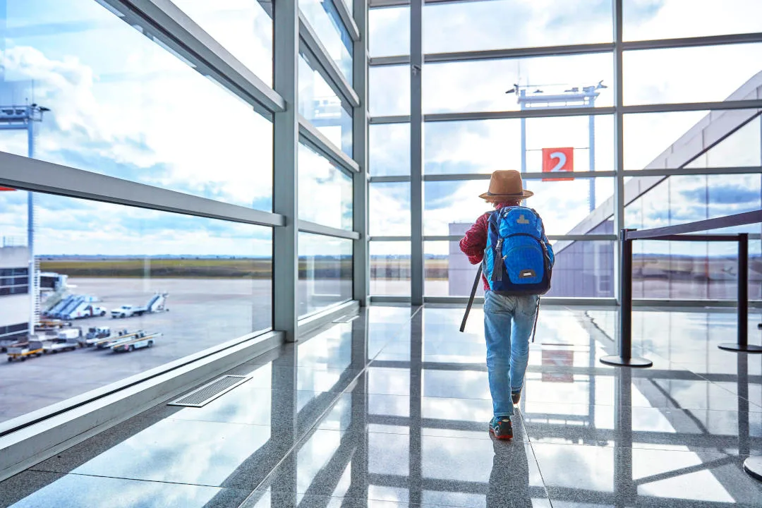 Boy with backpack at the airport running towards departure gate